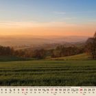 Kalenderseite: Monat Oktober, Tage sind nummeriert mit Wochentagen darunter. Landschaft mit Feldern bei Sonnenuntergang.