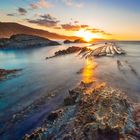 Keine Texte. Eine beeindruckende Meereslandschaft bei Sonnenuntergang mit sichtbaren Felsen im Wasser.