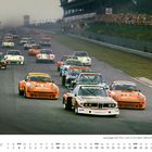 "Jägermeister" auf orangefarbenem Rennwagen. Vorne mehrere Sportwagen auf Rennstrecke, Zuschauer rechts. "OKTOBER" unten.