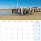 „Föhr Meine Insel“, Kalender für Oktober 2027. Bild: Ein Steg mit zwei Fahnen auf dem Sand vor klarem Himmel.