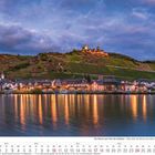 "Die Mosel von Trier bis Koblenz – Blick über die Mosel nach Alken." Abendliche Lichter spiegeln sich im Wasser.