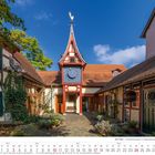 Kalender Oktober 2027, Fachwerkgebäude mit Uhrturm, Schild "Malerei", blauer Himmel im Hintergrund.
