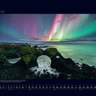07 Juli. Darunter ein Naturbild mit Nordlichtern über einer felsigen Küste und einem bogenförmigen Felsen.