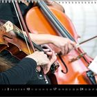 Kalender mit Monatsübersicht, darunter Musizierende mit Geige und Cello, ein Notenständer sichtbar.