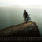 Kalender für den Monat November. Person mit Fahrrad steht auf einer Klippe, blickt aufs Meer.