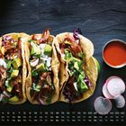 Kalender mit Tagen, Mo-So, 1-30 unten. Drei Tacos gefüllt mit Avocado, Fleisch, Koriander. Sauce und Radieschen daneben.