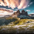 Kalender zeigt Oktober, Landschaft: Drei Zinnen in Dolomiten. Bergkulisse bei Sonnenuntergang, grasbewachsene Hänge.