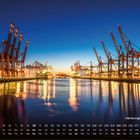 "Hamburger Hafen", darunter der Kalender Oktober. Hafenkräne spiegeln sich im Wasser, beleuchtete Abendstimmung.