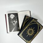 Ein Buch zeigt einen schwarz-weißen Dialog. Zwei weitere schwarze Bücher mit goldener Verzierung liegen darauf.