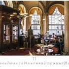 Text: "Café Central"

Beschreibung: Elegantes Café mit hohen Decken, großen Fenstern und sitzenden Gästen an Tischen.