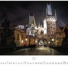 Karlsbrücke, 11, Casares Edition. Nachtaufnahme einer beleuchteten Brücke mit historischen Türmen und Statuen.