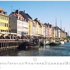"Kopenhagen, Nyhavn" und "CASARES EDITION". Eine Reihe bunter Häuser am Wasser, Boote im Kanal, Menschen am Ufer.