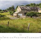 „CASARES EDITION“ und Monat „11“. Steinbauernhaus in grüner Landschaft, Kiesweg, Zaun und Bach; bewölkter Himmel.