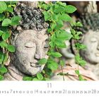 11. Eine steinerne Buddha-Statue, überwachsen mit grünen Blättern, im Vordergrund.