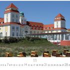 „Kurhaus Binz“; „CASARES EDITION“. Gebäude mit Türmen und roten Dächern, vorne Strandkörbe.