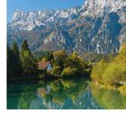 Text: TAUERNRADWEG. Eine idyllische Landschaft mit See, kleinem Haus, Bäumen und eindrucksvollem Berg im Hintergrund.