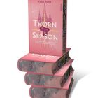 "Thorn Season" von Kiera Azar. Rosa Cover mit Rosen, Burgen und goldenen Akzenten. Ein Stapel Bücher.