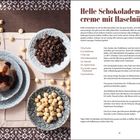 Helle Schokoladeneiscreme mit Haselnüssen. Drei graue Schalen: Eis mit Sauce und Nüssen, Kaffeebohnen, Haselnüsse. Dekoratives Tuch.