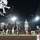 Fahne mit Totenkopf, Schriftzug "St. Pauli". Fußballspiel, Spieler in braunen und weißen Trikots im Stadion, November 2027.