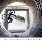 Kalender unten zeigt den November. Ein Radfahrer macht einen Handstand mit Fahrrad in einem Betonrohr.