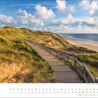 Monat: November. Kalender mit Dünenweg aus Holz, Sandstrand und Meer unter blauem Himmel mit Wolken im Hintergrund.