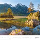 November. Landschaft mit klaren See, zwei kleinen Inseln und schneebedeckten Bergen im Hintergrund.