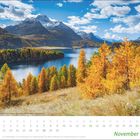 Kalendertext: November. Herbstlandschaft mit bunten Bäumen, Gebirge und blauem See unter blauem Himmel mit Wolken.