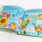 Text: Bestäubung. Emilie besucht eine Blumenwiese. Illustration: Bienen fliegen um bunte Blüten, um Bestäubung zu zeigen.