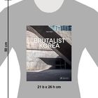 "BRUTALIST KOREA" von Paul Tullett. Graues T-Shirt mit einem Bild moderner Architektur in Betonoptik. Maße: 21 b x 26 h cm.