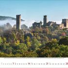 Kalenderseite mit November 2023. Ruinen einer Burg auf einem bewaldeten Hügel, umgeben von Nebel.