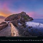 November 2023. Ein gewundener Weg führt zu einer felsigen Insel unter einem farbenfrohen Sonnenuntergangshimmel. 