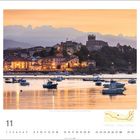 San Vicente de la Barquera, Spanien. Kalenderseite mit November-Daten. Abendstimmung über Wasser, Boote und historische Gebäude.