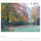 Unter einem Baum mit Herbstlaub sind bunte Blumen und ein einsamer Weg. Text: November 2027.