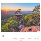Blick vom Buhlsteinturm, Sonne hinter Hügeln, bewaldete Felsenlandschaft, 11. Monat, Kalendarium darunter.