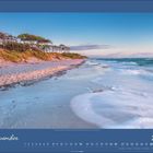 November 2027 Kalender. Sandstrand und Meer mit sanften Wellen, gesäumt von Bäumen und Dünen im Abendlicht.