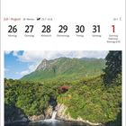 Kalender für Juli/August mit Landschaft: Wald, roter Brücke, Wasserfall und Bergen im Hintergrund.