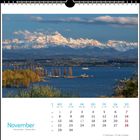 Kalenderseite November mit Blick auf schneebedeckte Berge und See im Vordergrund, Boote und Bäume in herbstlichen Farben.