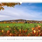 November. Herbstlicher Blick auf Kurort Hartha. Ein Feld mit buntem Herbstlaub im Vordergrund und Wälder im Hintergrund.