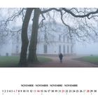 Text: November in vier Sprachen. Kalenderdaten. Ein nebliger Park mit einem weißen Gebäude und kahlen Bäumen.