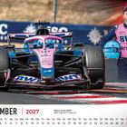 November 2027 Kalender, Rennwagen vorne, Fahrer steht rechts mit Helm. Farbtöne: Blau und Pink.