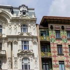 Gebäude mit reichem Stuck und Skulpturen auf der linken Seite, bunte florale Muster auf der rechten.