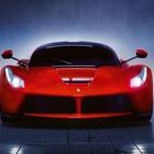 Ein rotes Sportauto mit hellem Scheinwerferlicht und einem kleinen, zentralen Logo auf der Motorhaube.