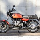 „BMW R80, Baujahre 1985-1995“ und „NOVEMBER“ stehen unter einem klassischen Motorrad vor einer Metallwand.