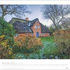 November 2027 | Die Insel Sylt. Ein Reetdachhaus mit blauem Tür und Ziegelmauern, umgeben von winterlichen Büschen.