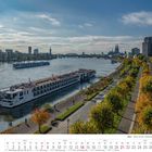 Kalenderseite November 2027. Am Rhein, Schiffe und Skyline von Köln, Bäume in Herbstfarben entlang der Promenade.