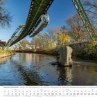 „Wuppertaler Schwebebahn – Störstein ‚Tuffi‘“. Eine Schwebebahn über einem Fluss, umgeben von Bäumen. Darunter ein Kalender.