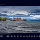 "11 November" oben links. Kalenderdarstellung unten. Herbstliche Insel mit Gebäuden, Wellen und Bergen im Hintergrund.