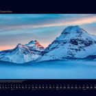 12 Dezember. Die Berge sind mit Schnee bedeckt, von Nebel umgeben, im Hintergrund pastellfarbener Himmel.