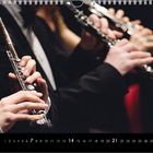 Text: "11, 7, 14, 21, 28" unten. Musiker spielen Flöten, nah aufgenommen, mit eleganten, dunklen Anzügen.