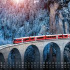 Kalenderblatt Dezember: Roter Zug auf einer Steinbrücke vor schneebedecktem Wald. Sonnenlicht im Hintergrund.